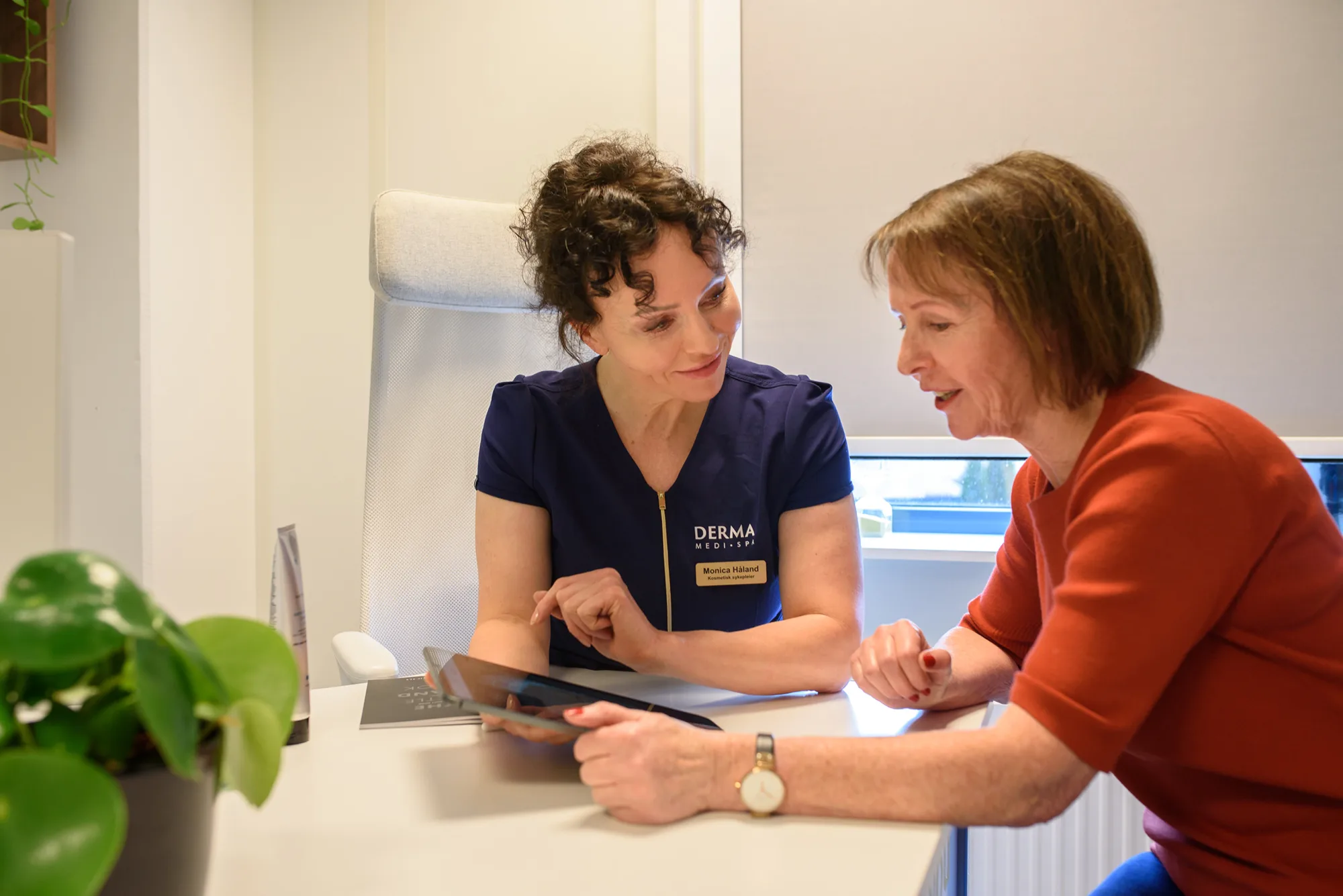 Kosmetisk sykepleier gjennomg&aring;r hudanalysen sammen med en kunde p&aring; Derma MediSpa